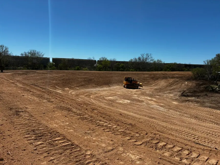 Dozer working inside a freshly graded earthwork basin under a clear blue sky