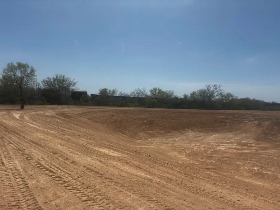 Smooth graded dirt pad with a tree line behind
