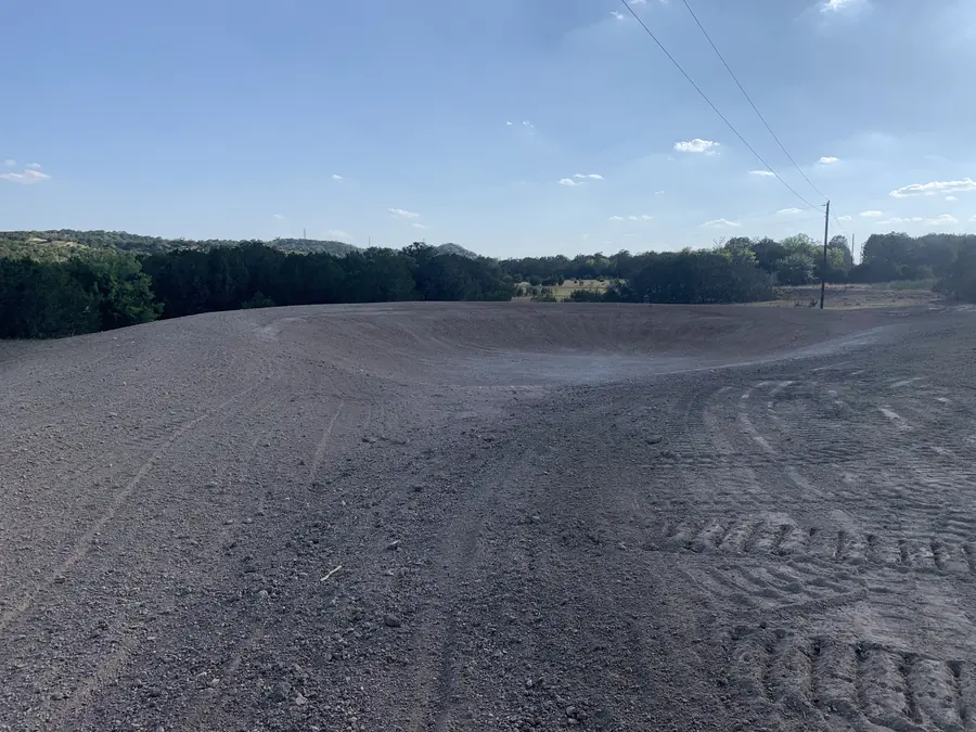 Freshly graded earthen basin with wooded hills behind