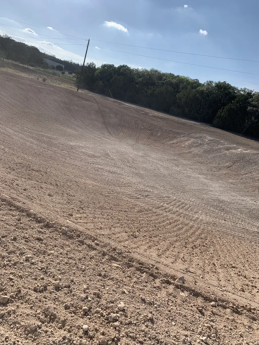 Long graded bank rising toward a tree line