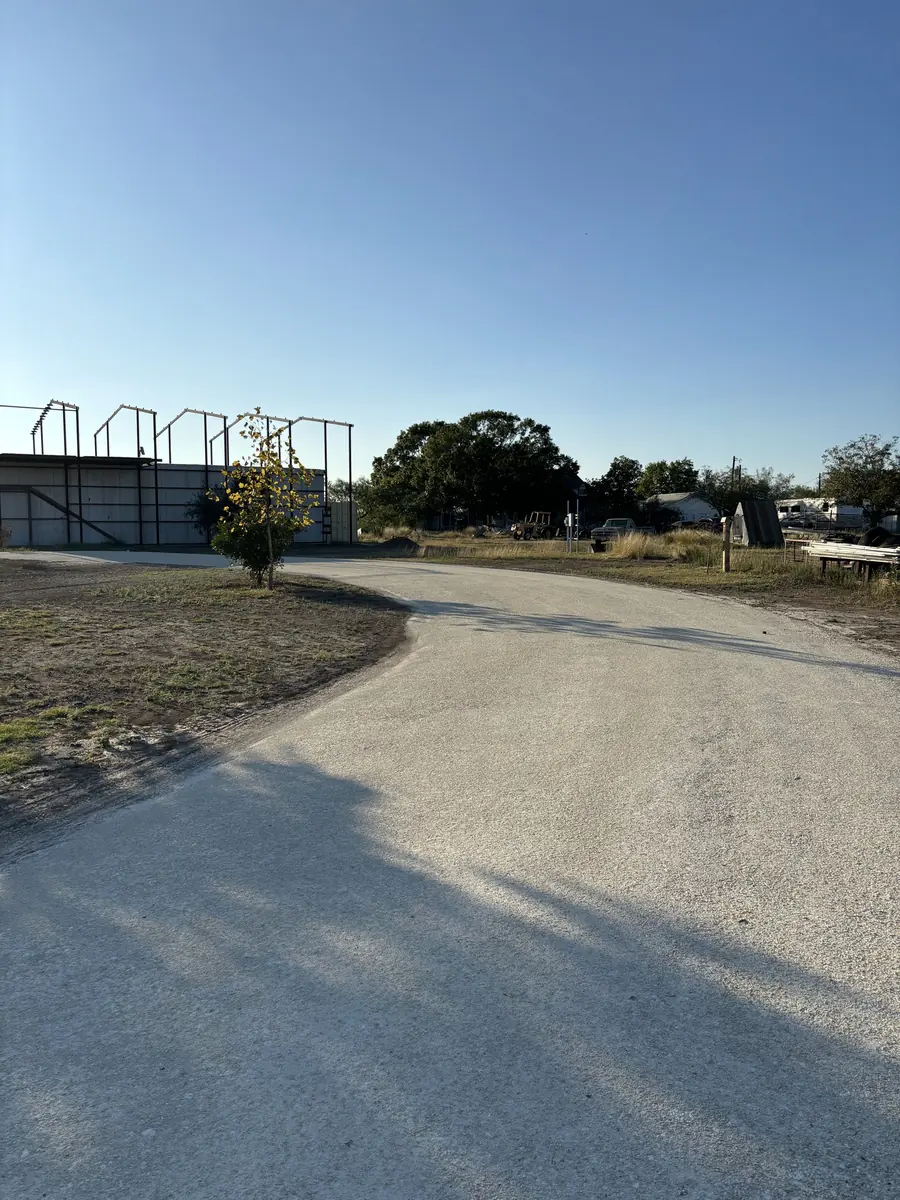 Pale gravel drive curving past a steel building frame