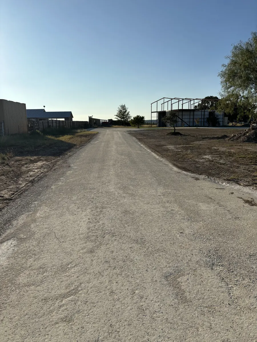 Pale gravel drive leading in to metal buildings