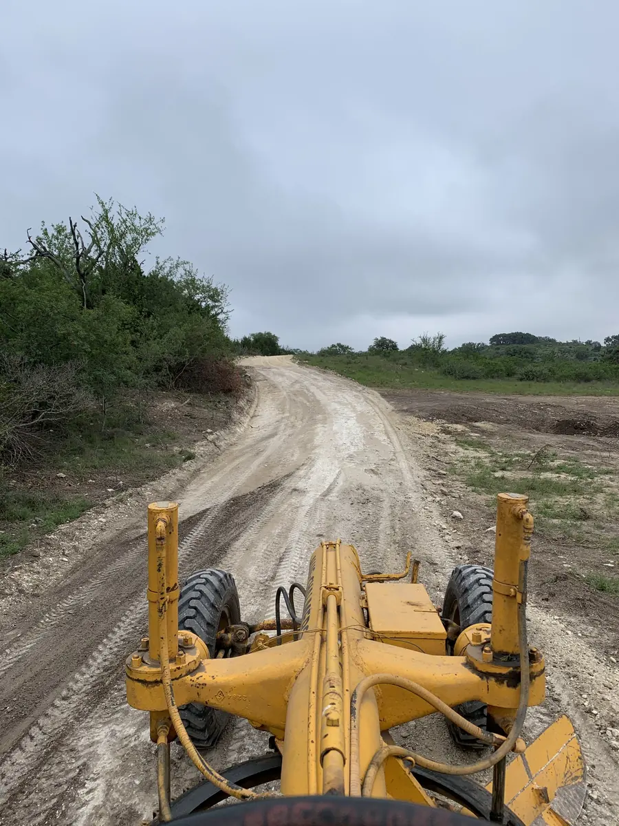 The front of a motor grader on a freshly graded road, seen from the seat