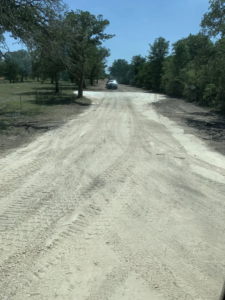 Wide graded lane under trees, with a vehicle far down the road